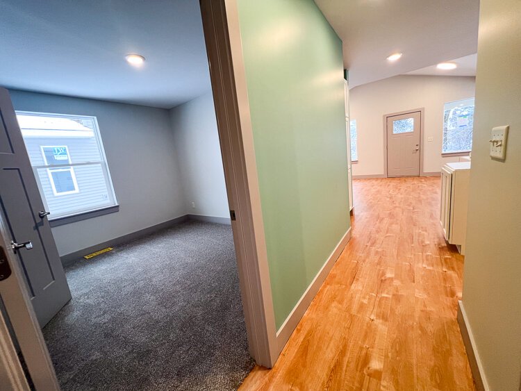 A hallway view of a single-unit home, where aging in place takes center stage. The accent wall in a refreshing green tone, seamlessly connects with the tree-lined front yards of this row of homes at 2080 Union.