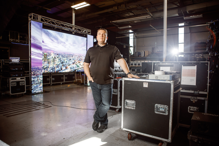 Todd Ernst stands in front of a massive backlit LED set up by LiveSpace. 