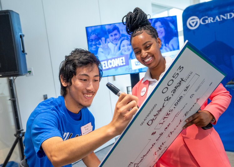 Grand Valley students Joy Murerwa and Kevin Wong sign the check from Fifth Third Foundation's nearly $2 million commitment Oct. 8.