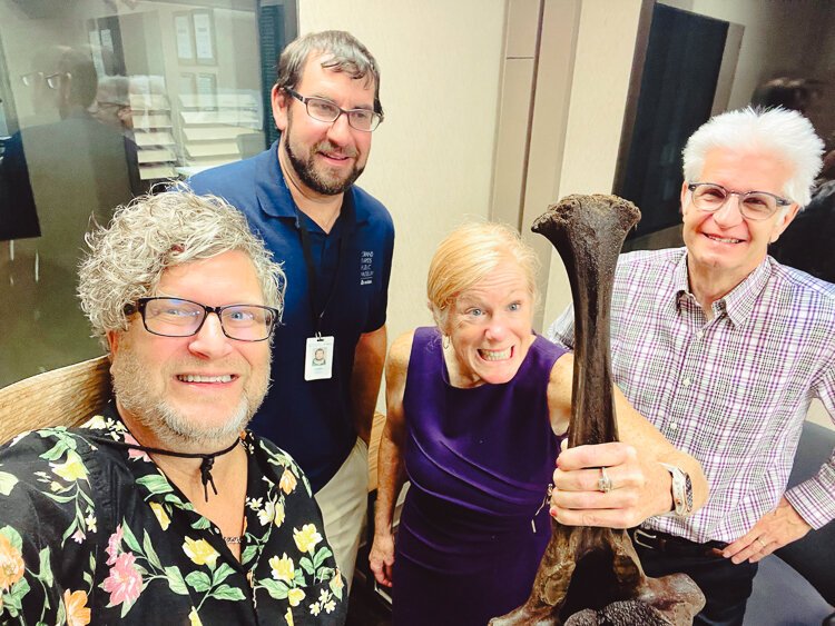 Dale Robinson (right) loves to take the museum out to the people. Shelley Irwin (center) holds a mastodon bone excavated in Kent County in  2022. 