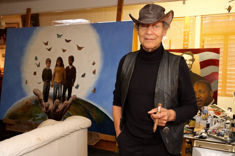 Artist Paul Collins in his studio with his signature cigar and favorite leather hat. 