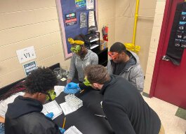 Teacher Jake Rewa works with students in a science lab.