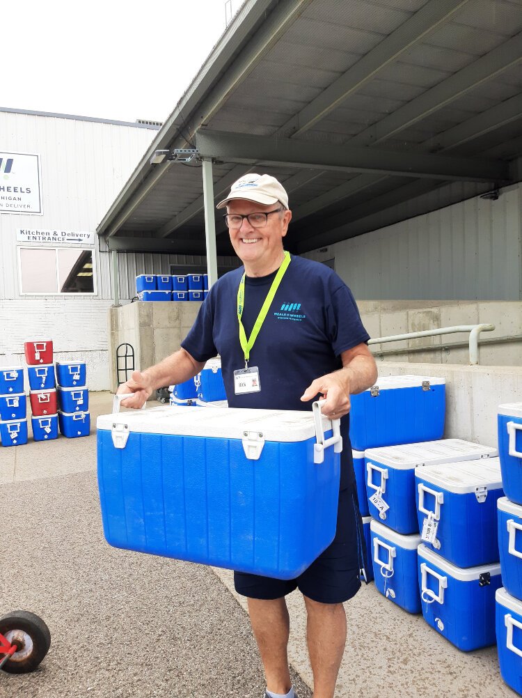 A dedicated volunteer transports coolers of Home Delivered Meals into their vehicle for delivery.