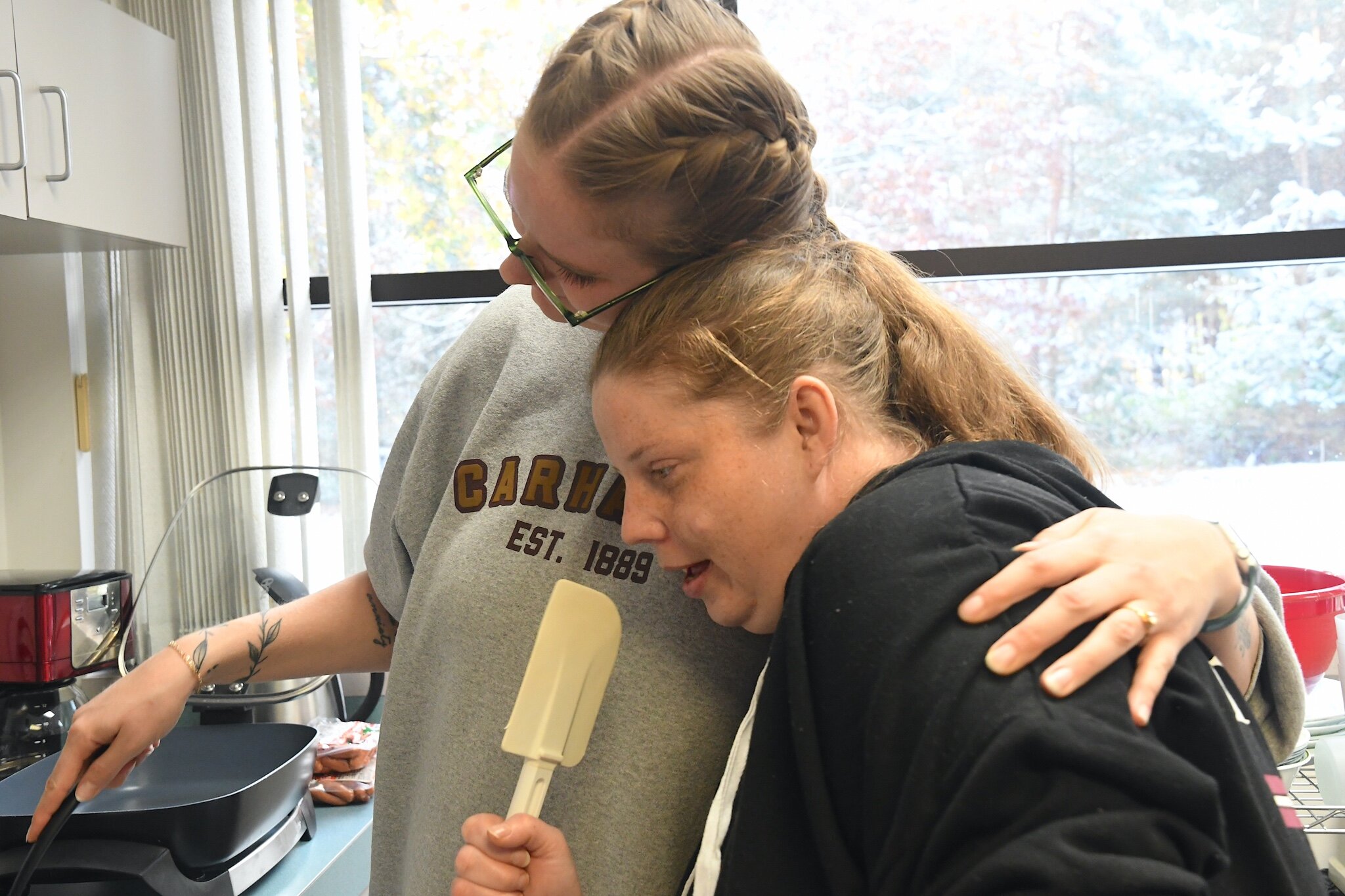 Natalie Visser, an assistant supervisor for MOKA, left, and Tracy share a warm embrace during a life skills session on cooking at a MOKA site in Wyoming.