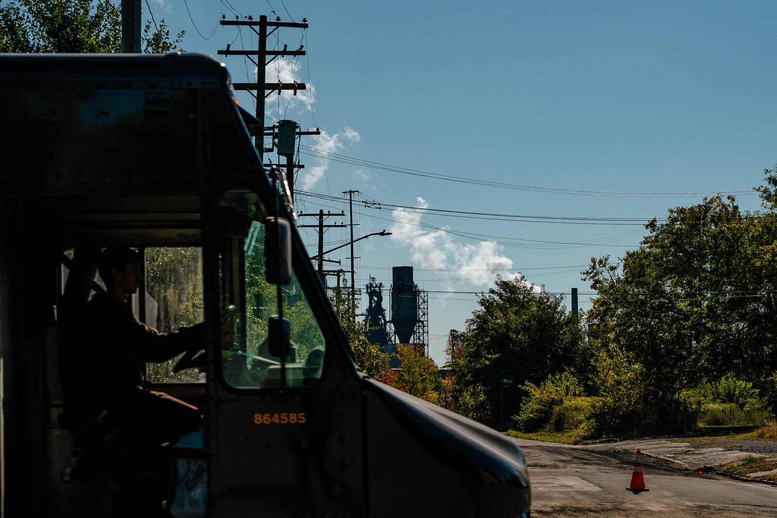 In Detroit, a truck drives on Jefferson Ave. while smoke billows from Zug Island.